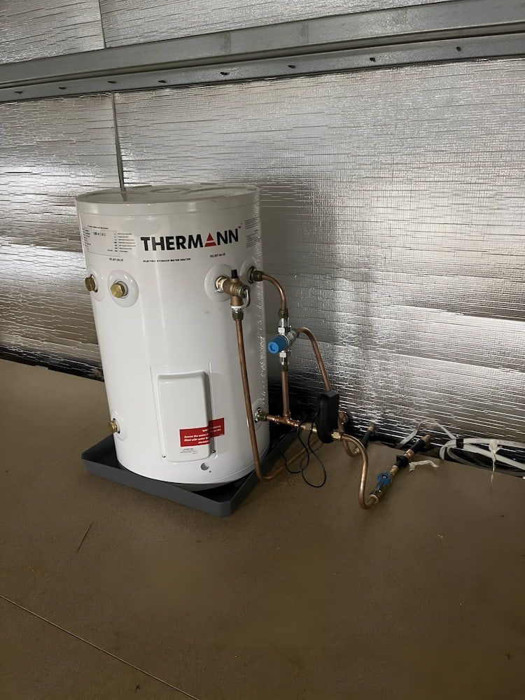 A White Water Heater is Sitting on a Tray Next to a Wall — John Day Plumbing in Marlow Lagoon, NT
