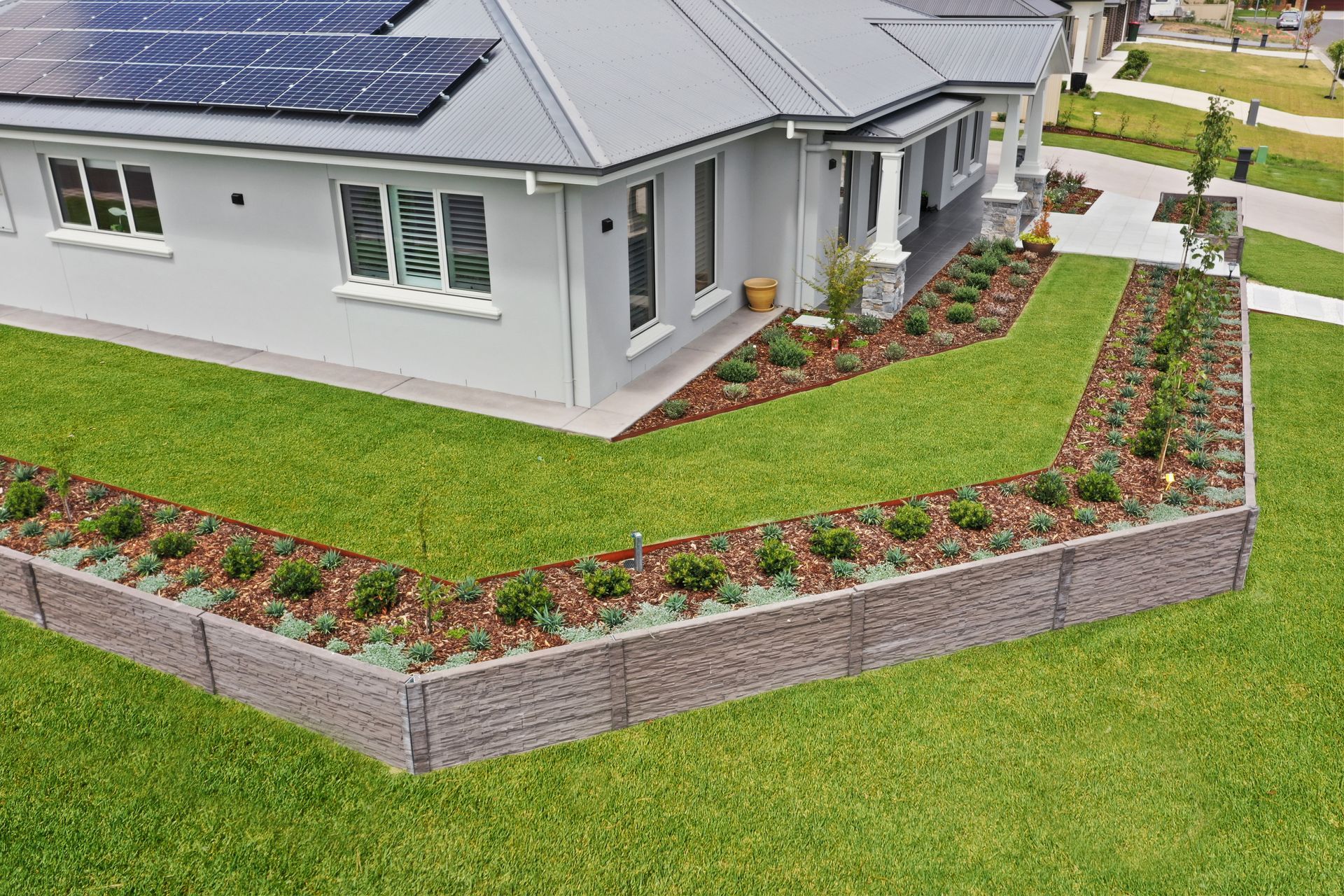 Modern landscape construction featuring concrete sleeper retaining wall, formal native garden and mnaicured lawn