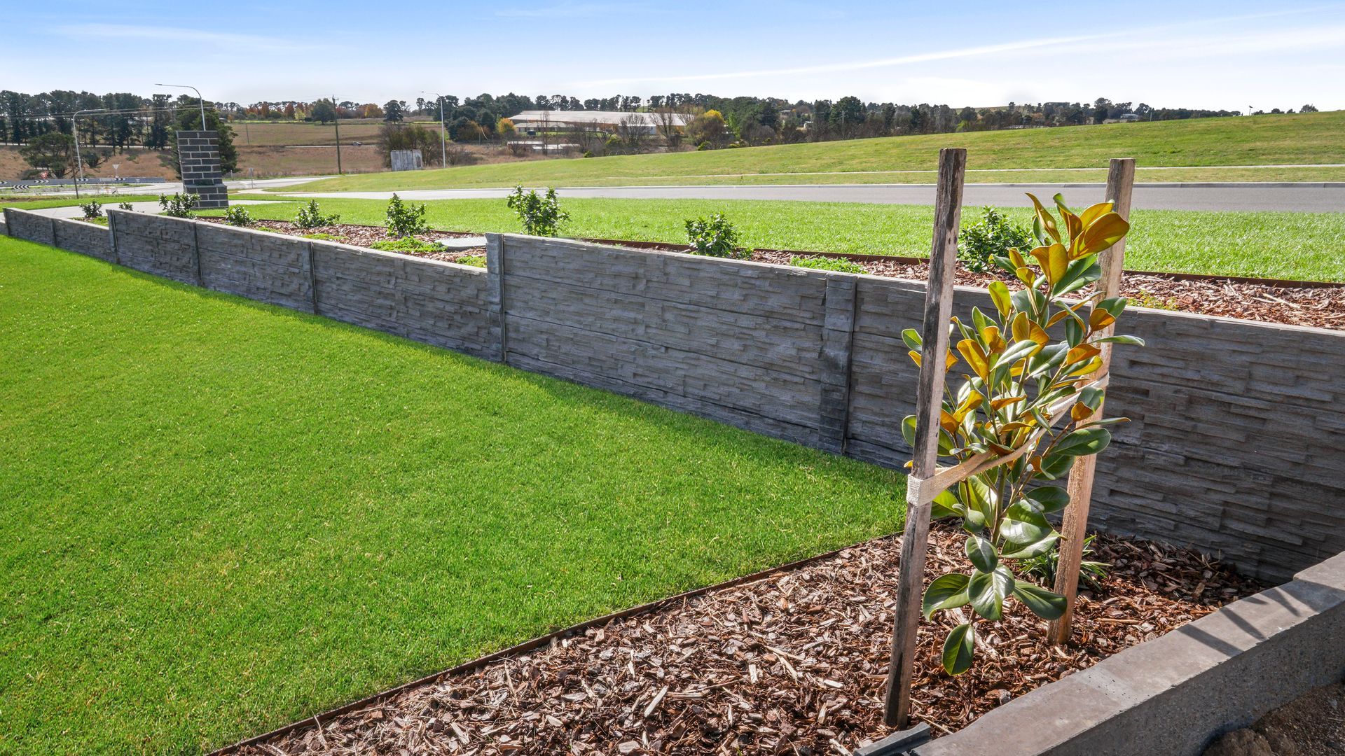 Formal landscape construction in Bathurst NSW- concrete sleeper retaining walls, native-exotic garden beds and manicured lawn