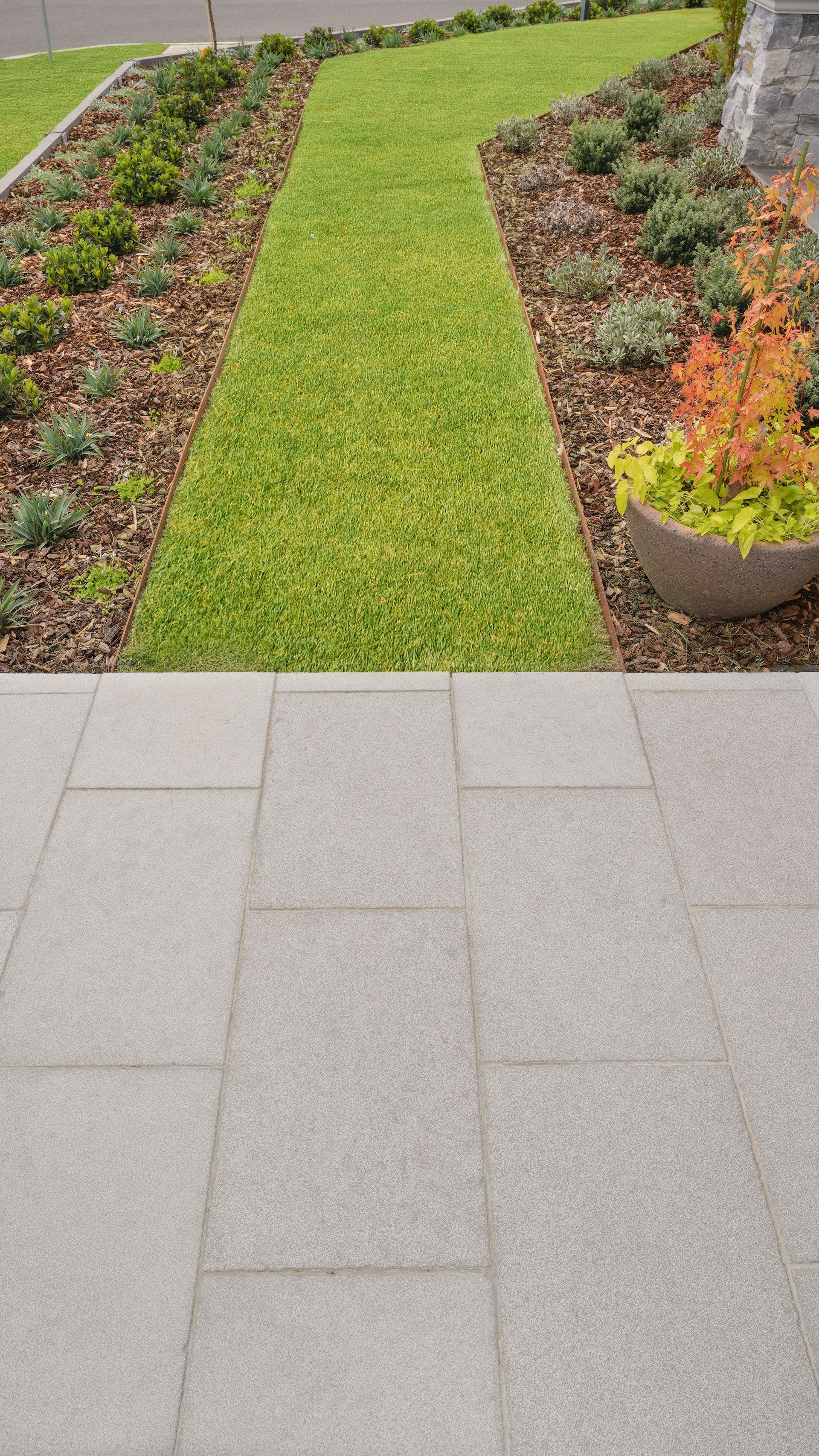 Modern front yard landscaping with paved entrance, native garden beds, and manicured lawn in a residential landscape construction project in Orange NSW