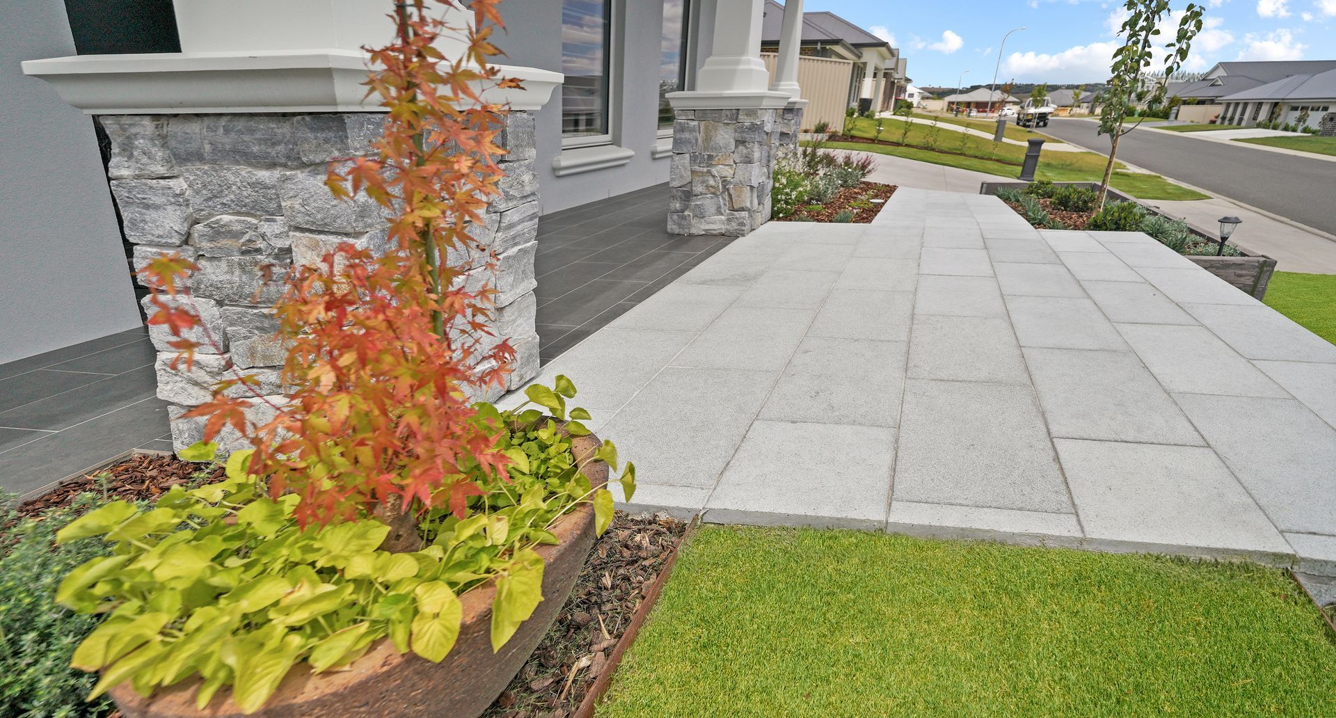 Modern landscape with paving area, stone cladding entrance and formal garden beds