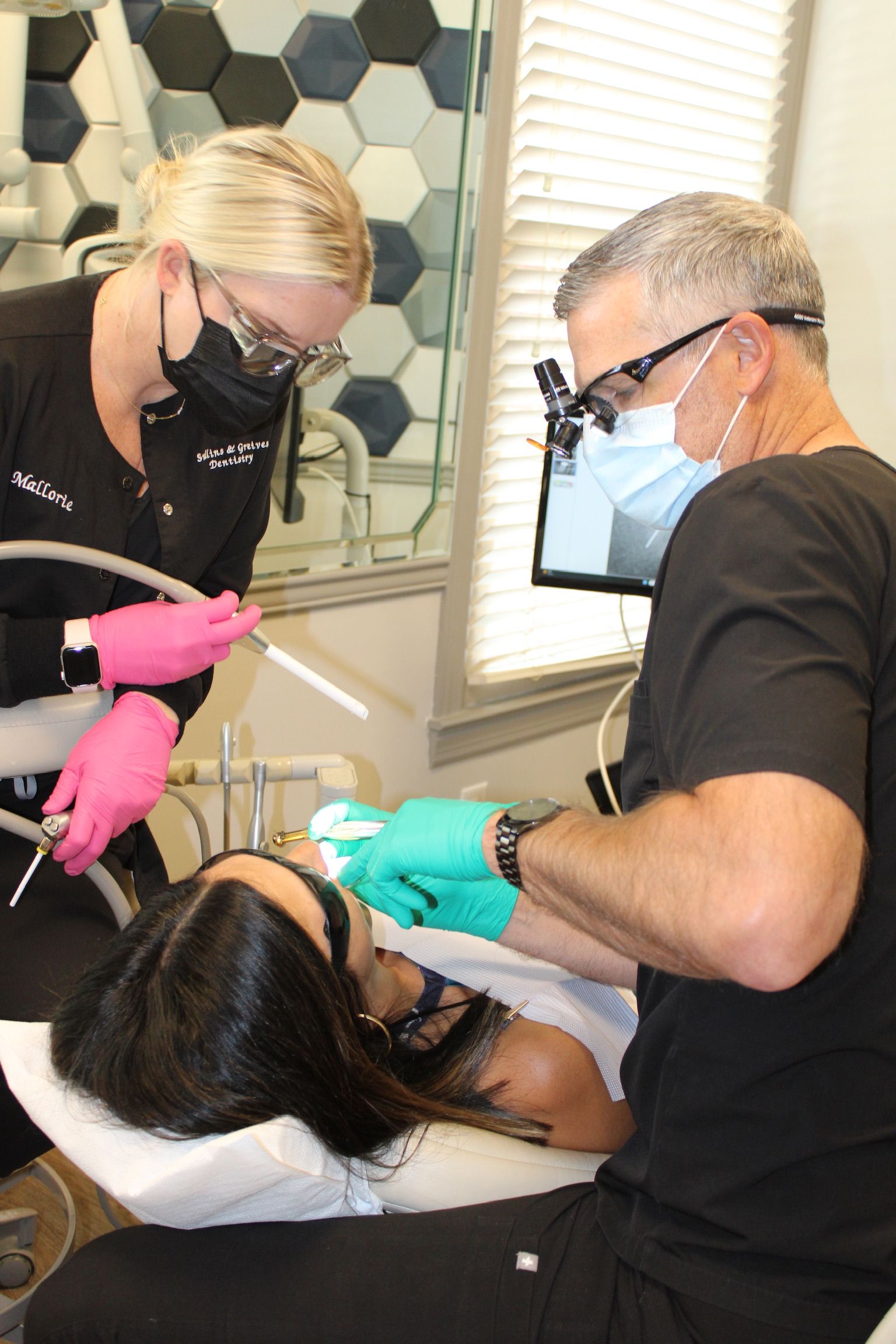 Dentist and assistant providing dental care to a patient in a clinic setting.