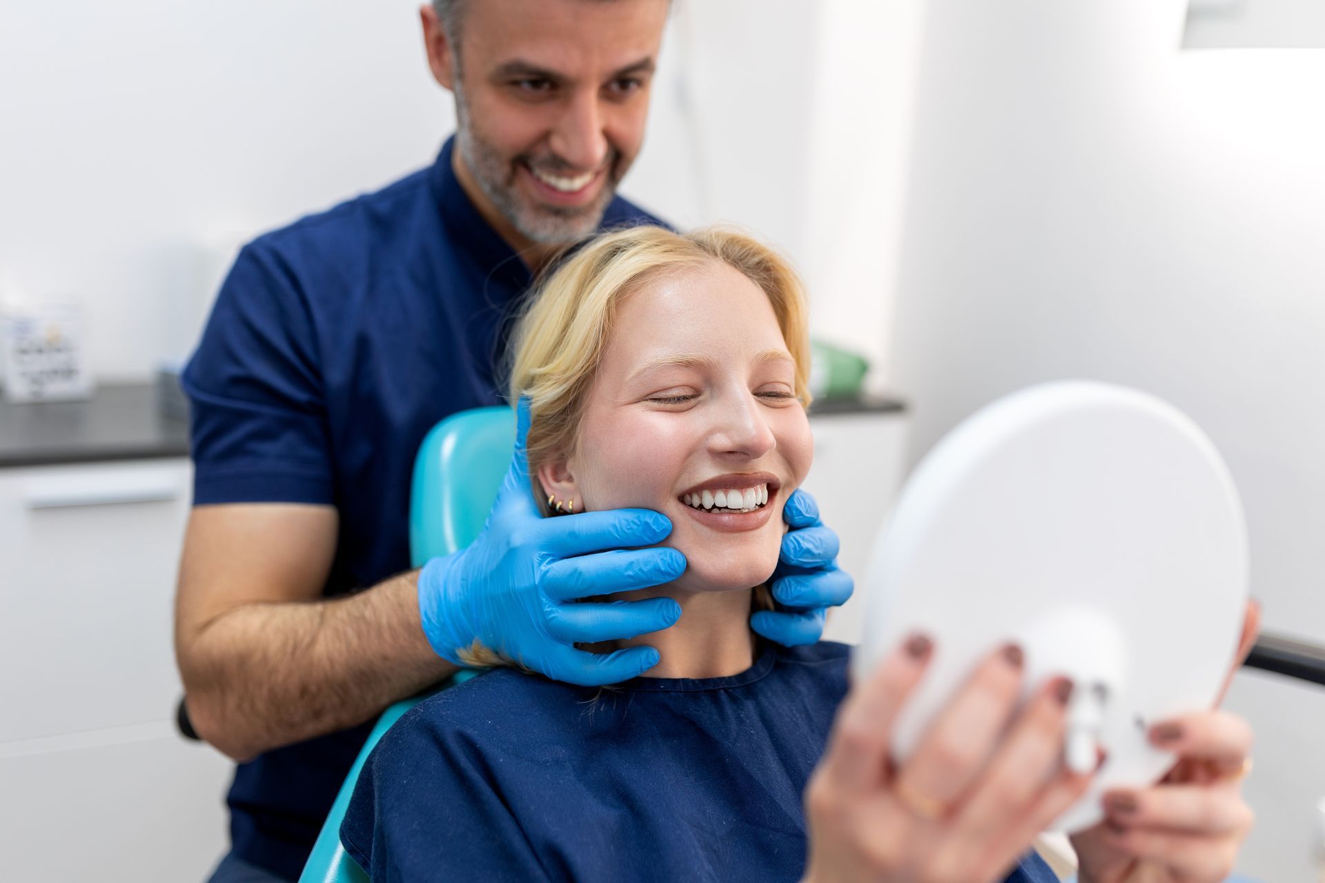 Dentist showing a patient her smile in a mirror; the patient is smiling.