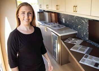 A woman in a black shirt is standing in a kitchen.