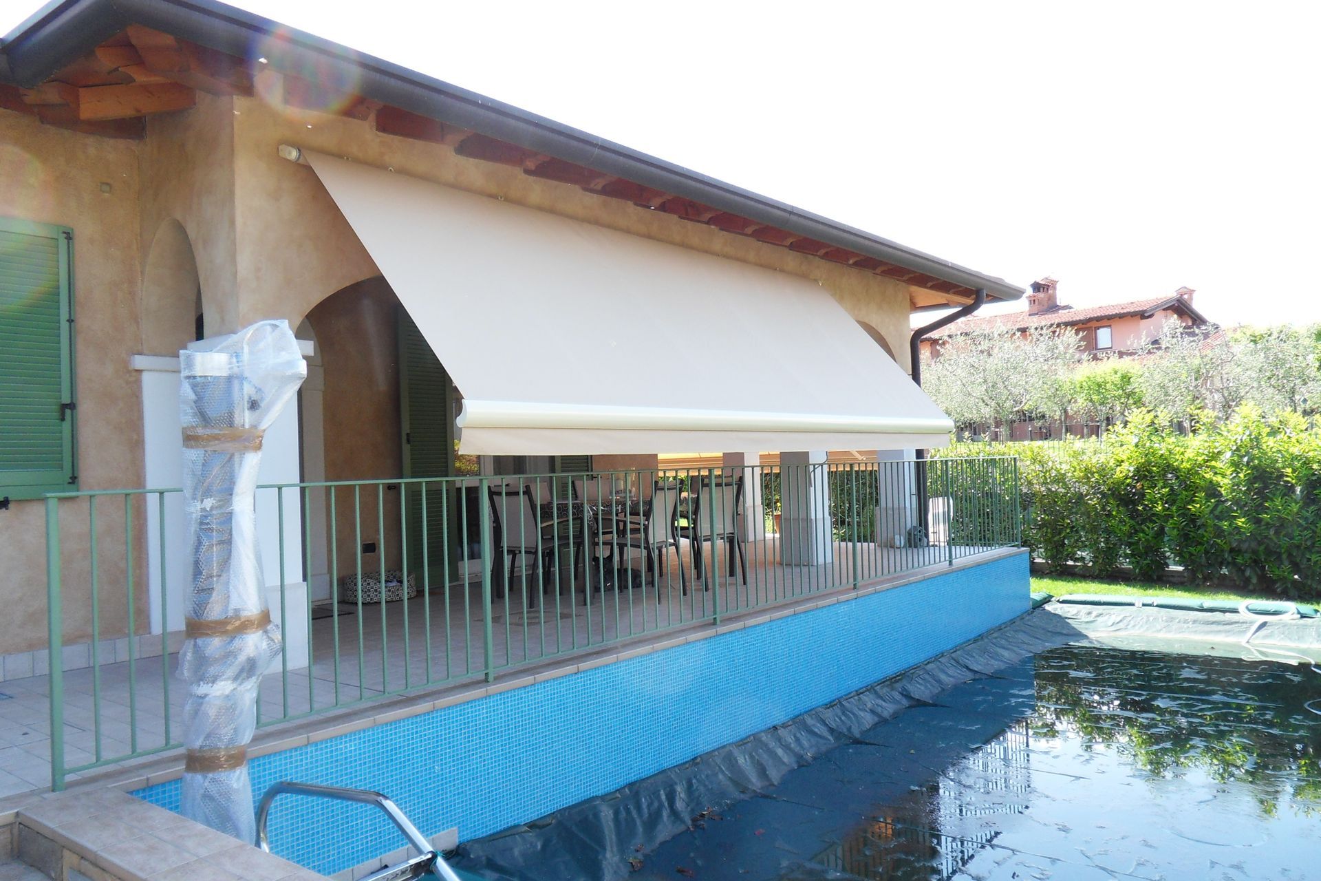 Tenda da sole beige sopra un patio con piscina. 