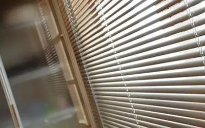 tende tecniche chiuse di una finestra, dalle quali filtra la luce del sole.