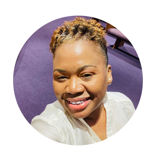 Woman with short, light brown hair wearing an orange sweater smiles at the camera.