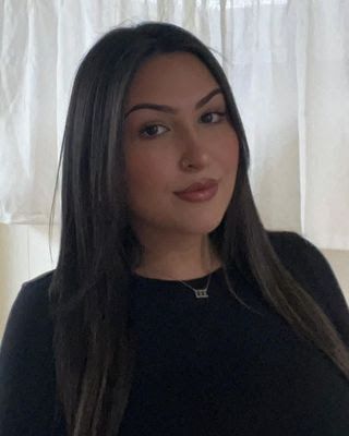 Woman with long dark hair, wearing a black shirt, looking at the camera.