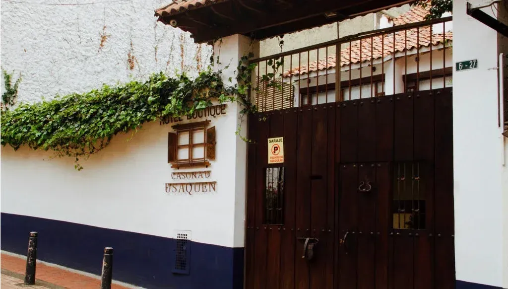 Puerta de madera y muro con enredaderas verdes, entrada del edificio.