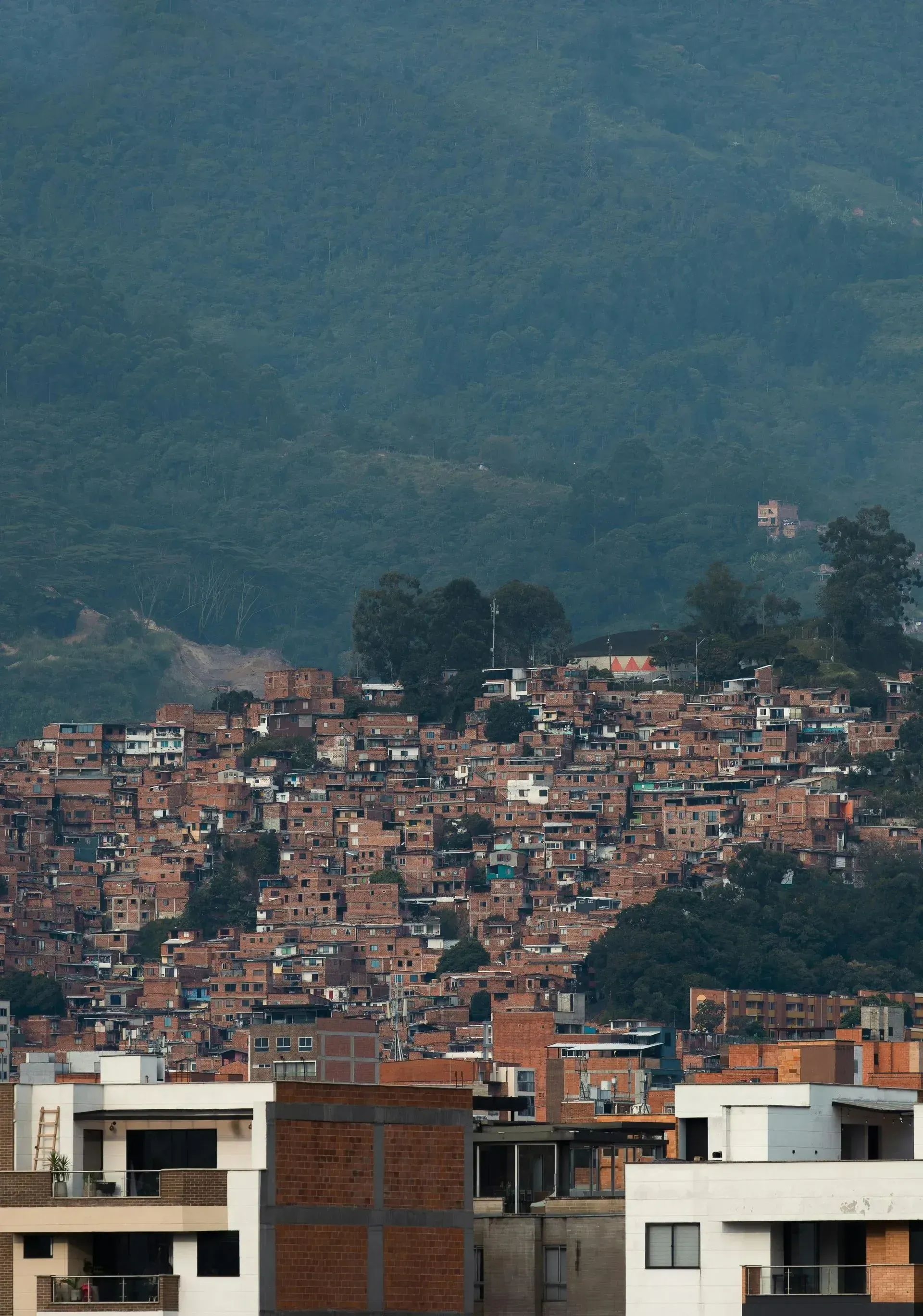 Edificios de la ciudad agrupados en una ladera, con un telón de fondo de montañas verdes.