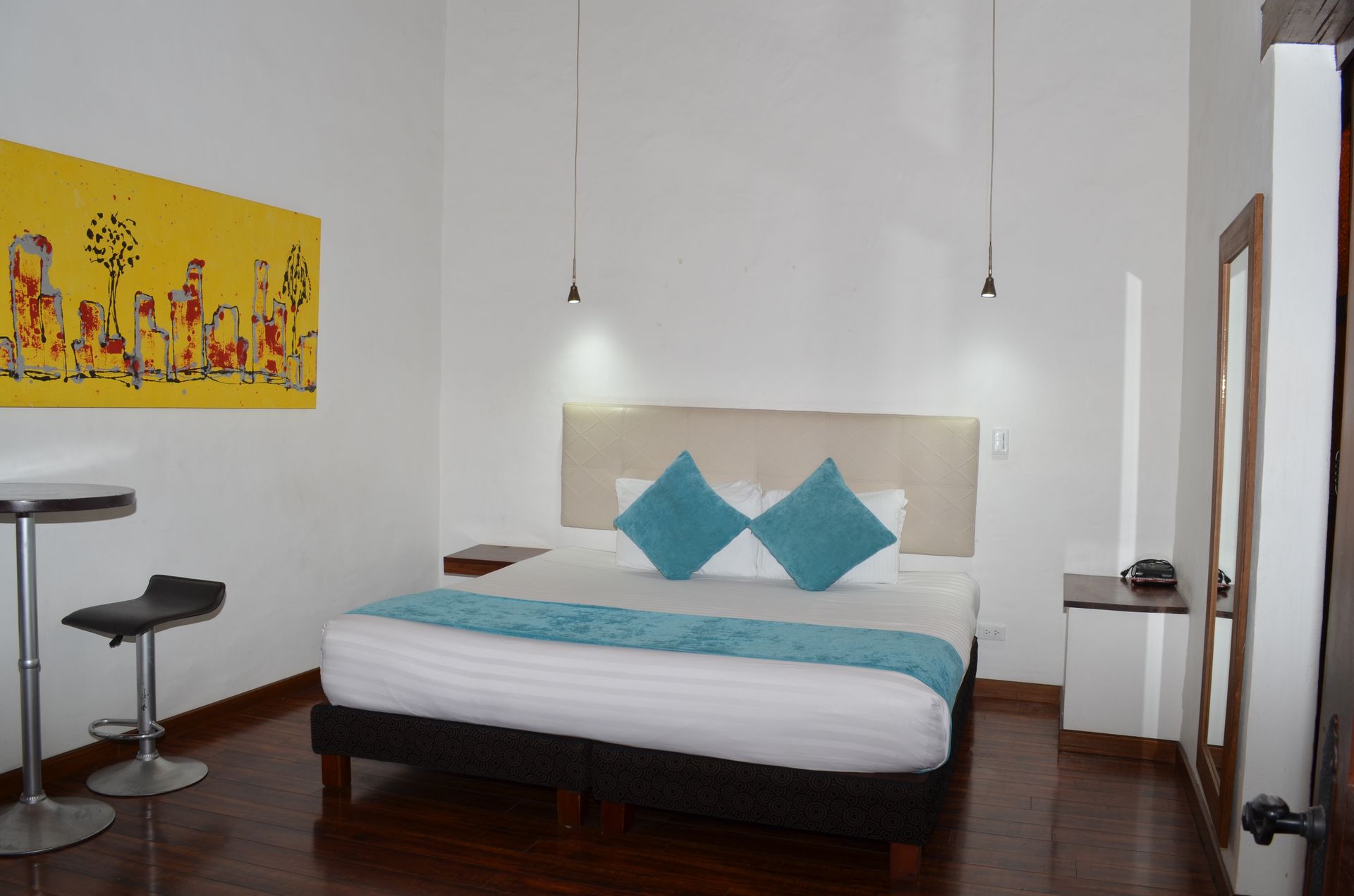 Dormitorio con cama, obras de arte y decoración minimalista. Detalles en azul claro sobre fondo blanco.