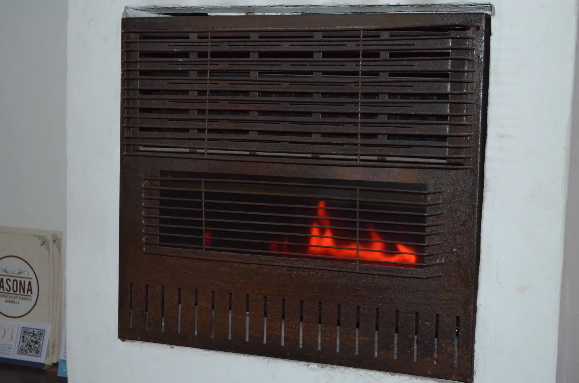 Una chimenea de gas con rejilla metálica y llamas visibles que emiten calor.