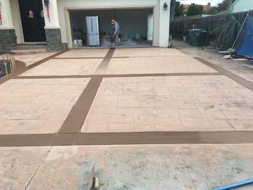 A concrete driveway is being painted in front of a house.