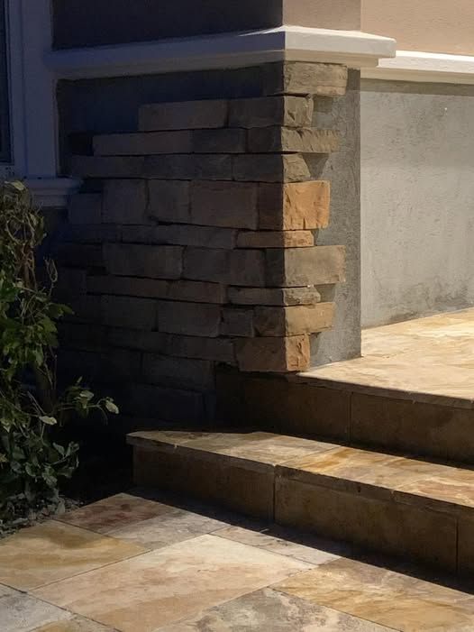 A stone wall with stairs leading up to it next to a building.