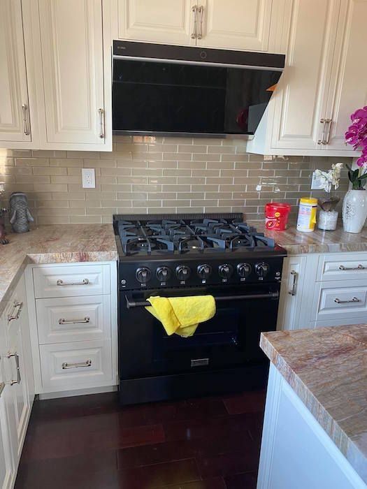 A kitchen with a black stove top oven and white cabinets.