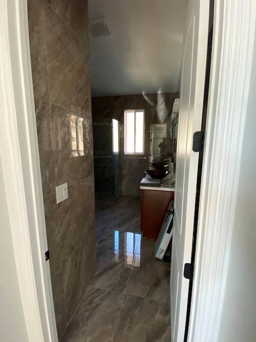 A hallway leading to a bathroom with a sink and a mirror.