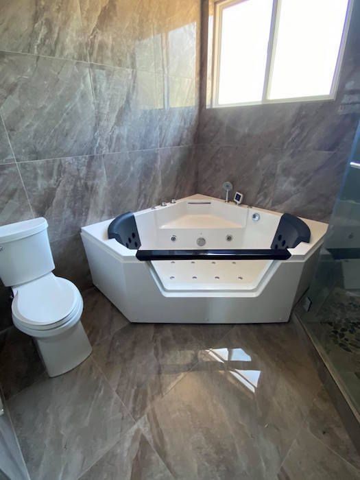 A bathroom with a jacuzzi tub , toilet and shower.