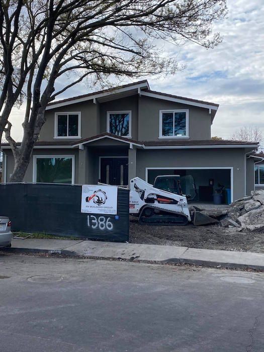 A house under construction with a bobcat in front of it.