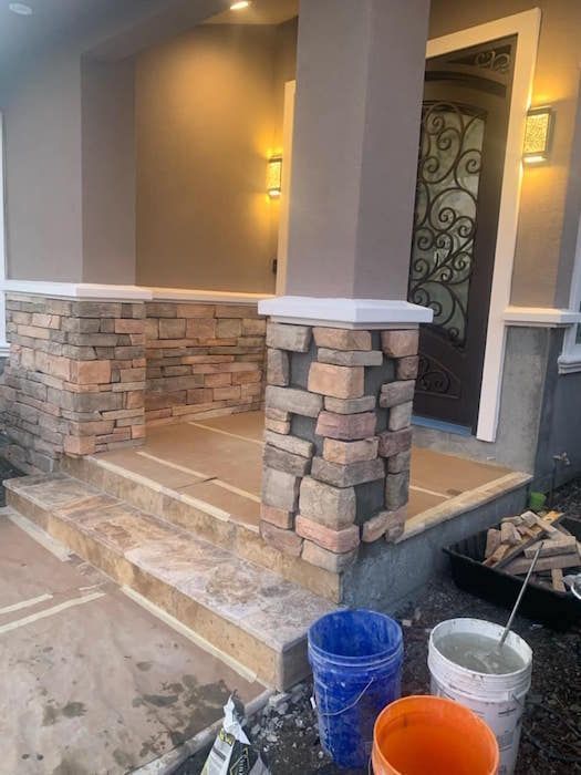 A stone porch is being built on the side of a house.