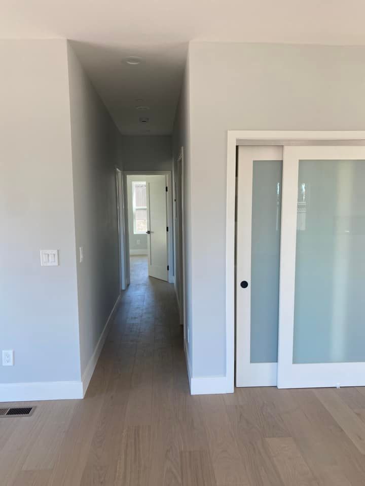 An empty hallway with a sliding glass door leading to a bedroom.