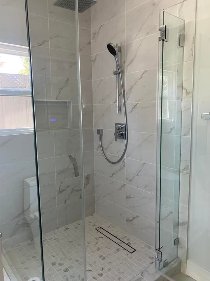 A bathroom with a walk in shower with a glass door and a shower head.