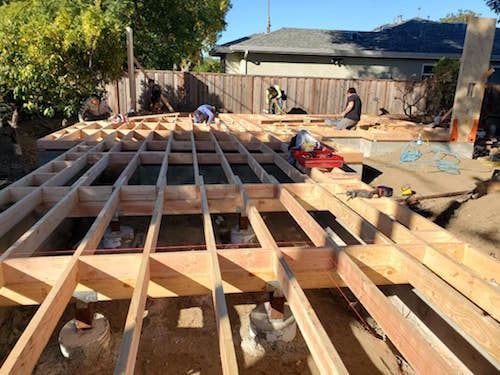 A wooden deck is being built in the backyard of a house.