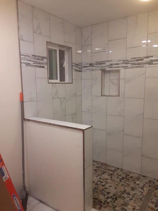 A bathroom with white tiles and a window.