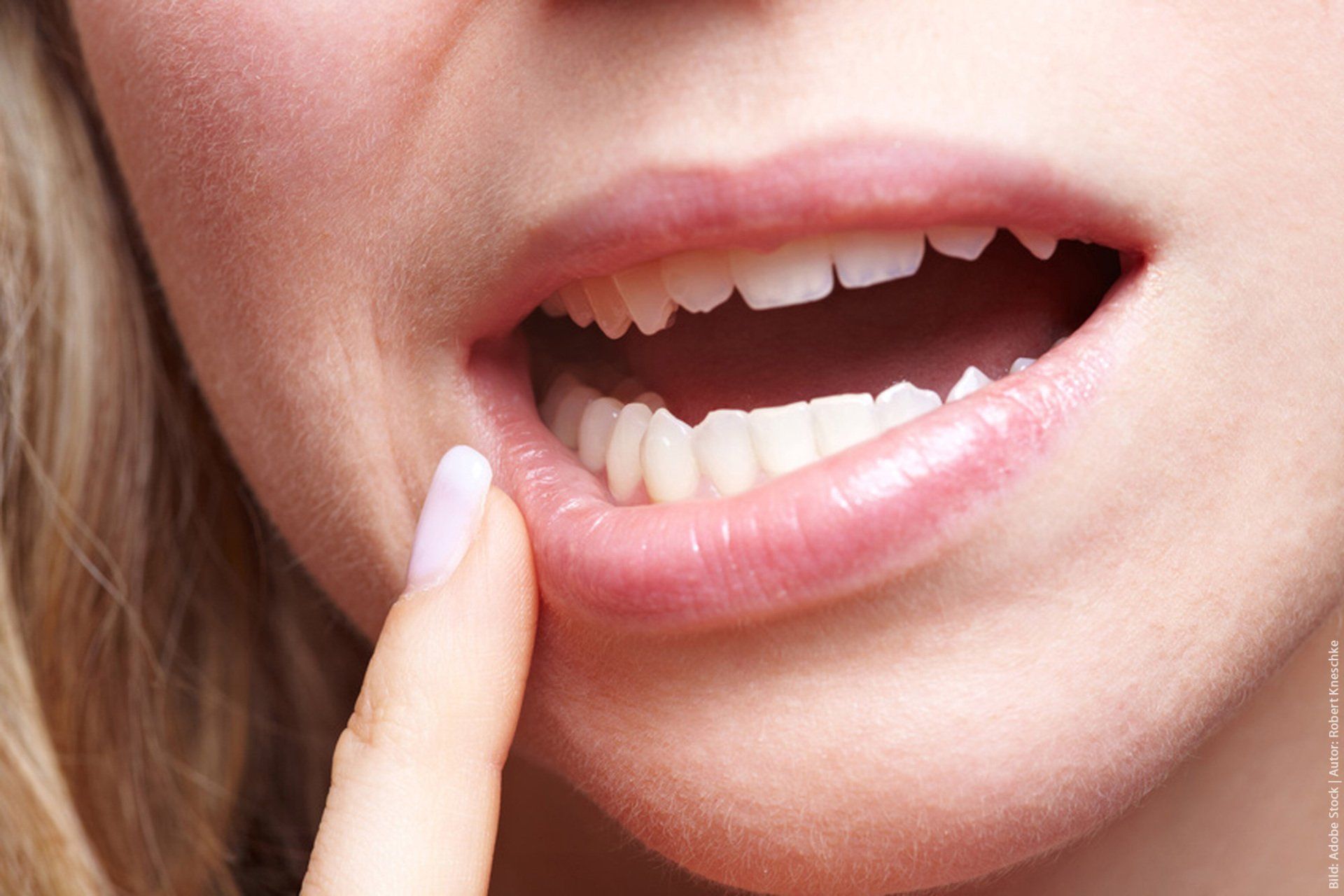 A close up of a woman 's mouth with her finger on her lip.