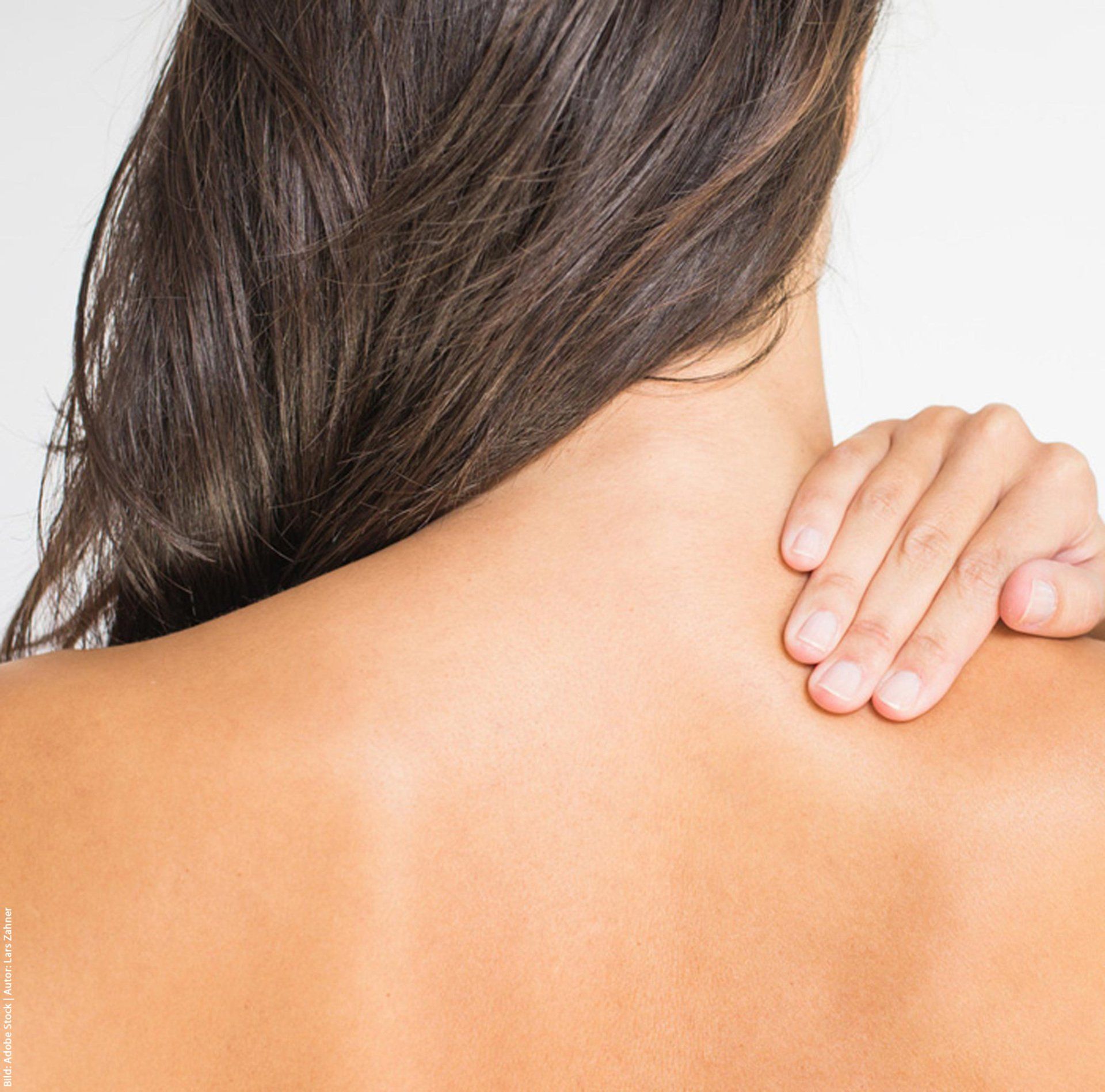 Eine Frau hält ihre Hand an ihrem Nacken.