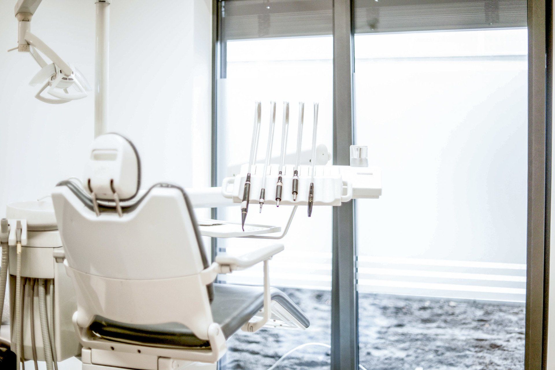 A dental chair is sitting in a dental office next to a window.