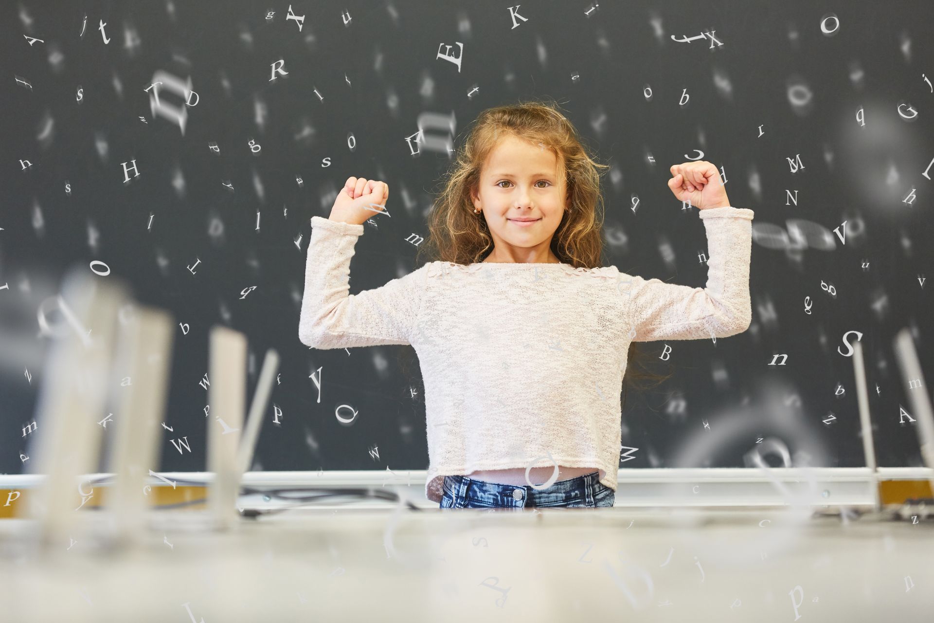 A girl posing with both arms up, surrounded by letters