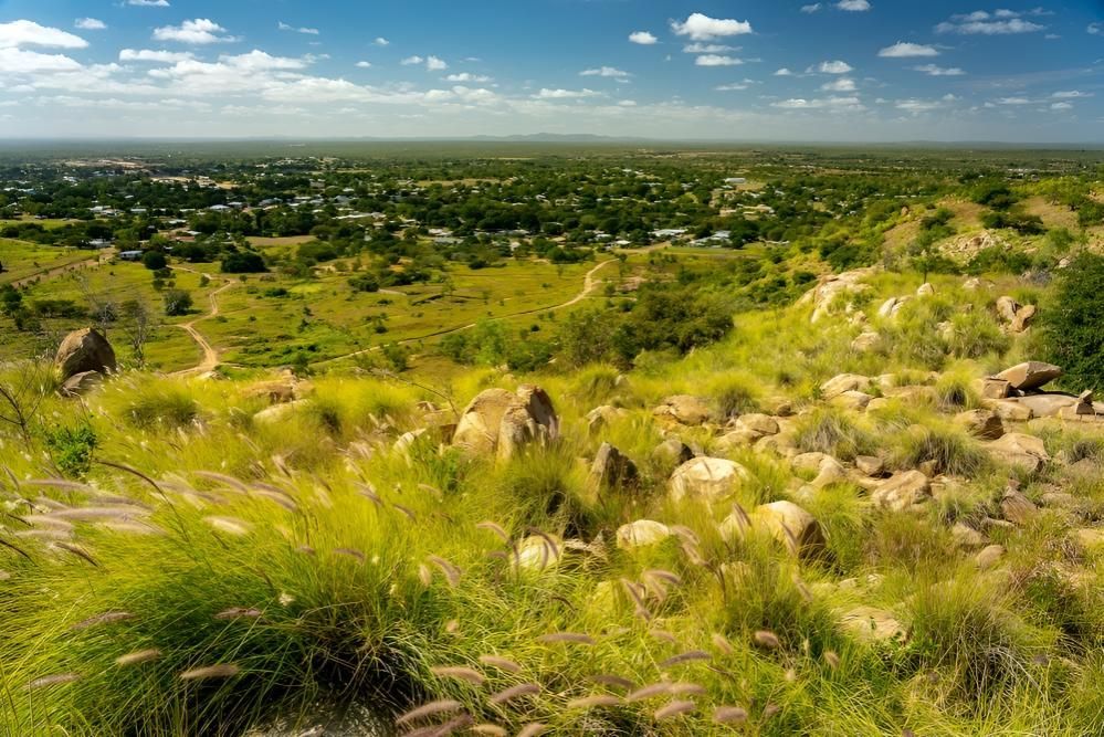 A View of a Lush Green Field With a Small Town in the Distance — Power & Data Support Services In Charters Towers, QLD