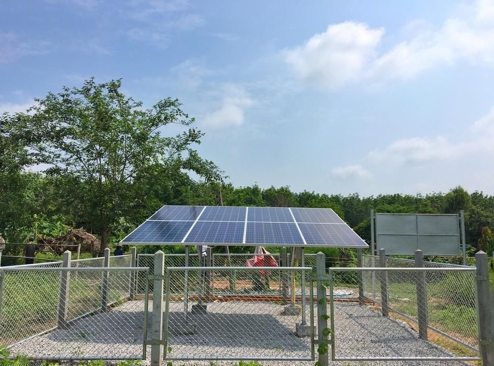 A Man is Working on a Solar Panel in a Fenced in Area — Power & Data Support Services In Mapoon, QLD