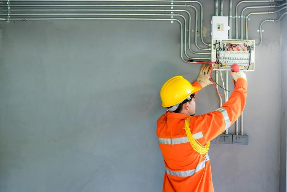 An Electrician is Working on an Electrical Box on the Wall — Power & Data Support Services In Mareeba, QLD
