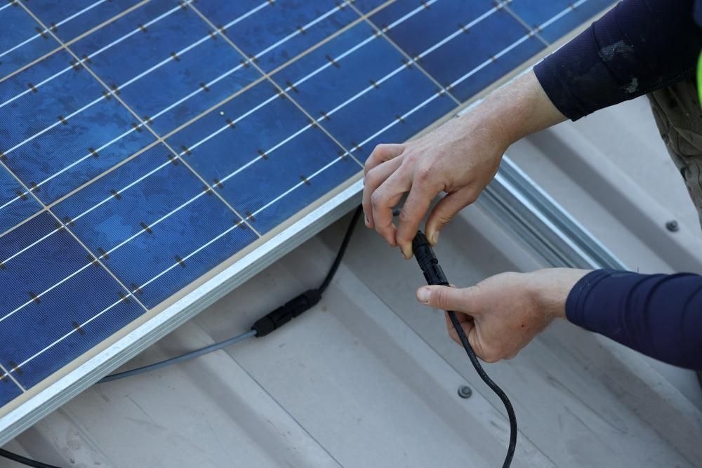 A Person is Installing a Solar Panel on a Roof — Power & Data Support Services In Tablelands, QLD