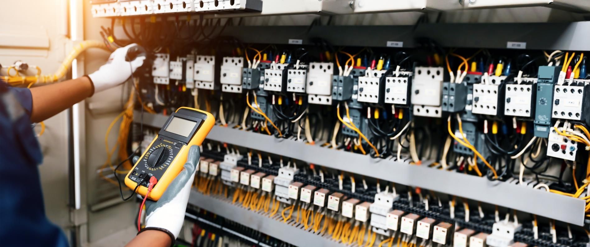 An Electrical Engineer is Working on a Control Panel in a Factory — Power & Data Support Services In Cardwell, QLD