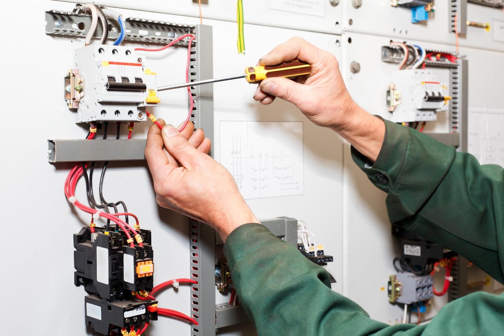 A Man is Working on an Electrical Panel With a Screwdriver — Power & Data Support Services In Charters Towers, QLD