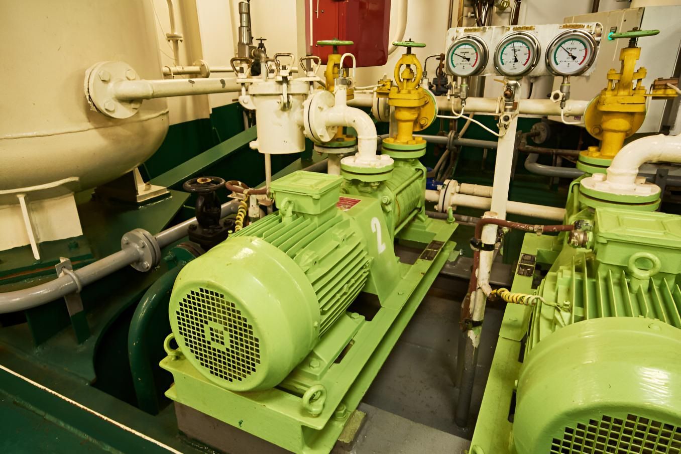 A Green Motor is Sitting in a Room With a Lot of Pipes and Gauges — Power & Data Support Services In Atherton, QLD