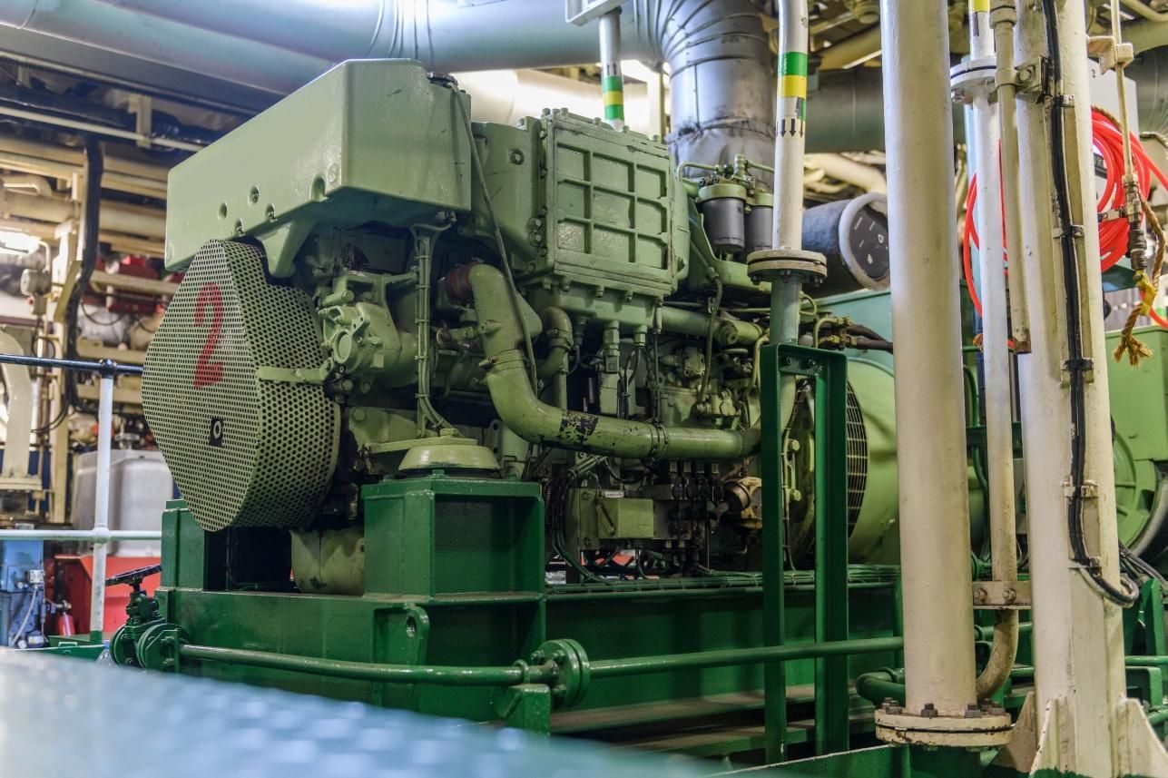 A Large Green Engine is Sitting in a Room on a Ship — Power & Data Support Services In Cardwell, QLD