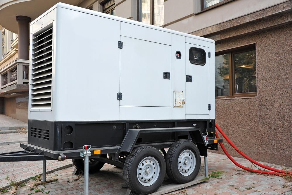 A White Generator on a Trailer is Parked in Front of a Building — Power & Data Support Services In Karumba, QLD
