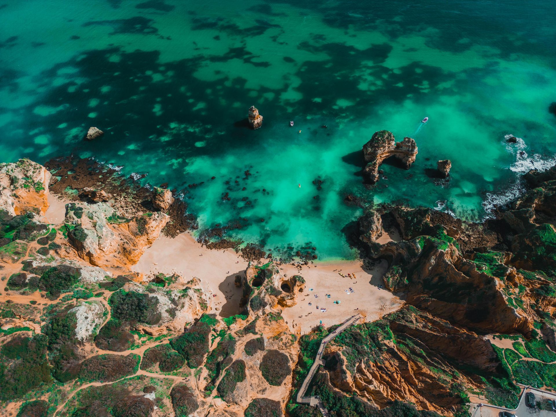 An aerial view of a beach surrounded by rocks and turquoise water.