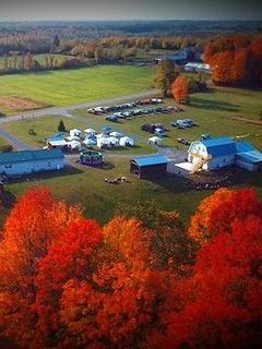 An aerial view of a farm surrounded by trees with red leaves.