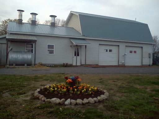 A white house with a blue roof and a flower bed in front of it