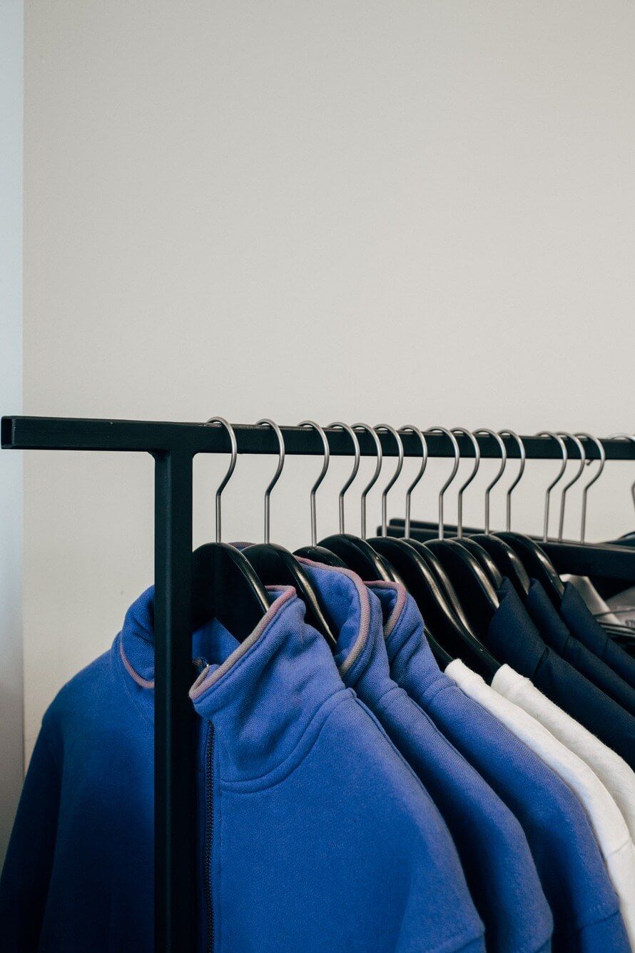 A Row Of Blue Sweatshirts Are Hanging On A Rack — Shop Fittings Office Furniture Materials Handling In Gosford, NSW