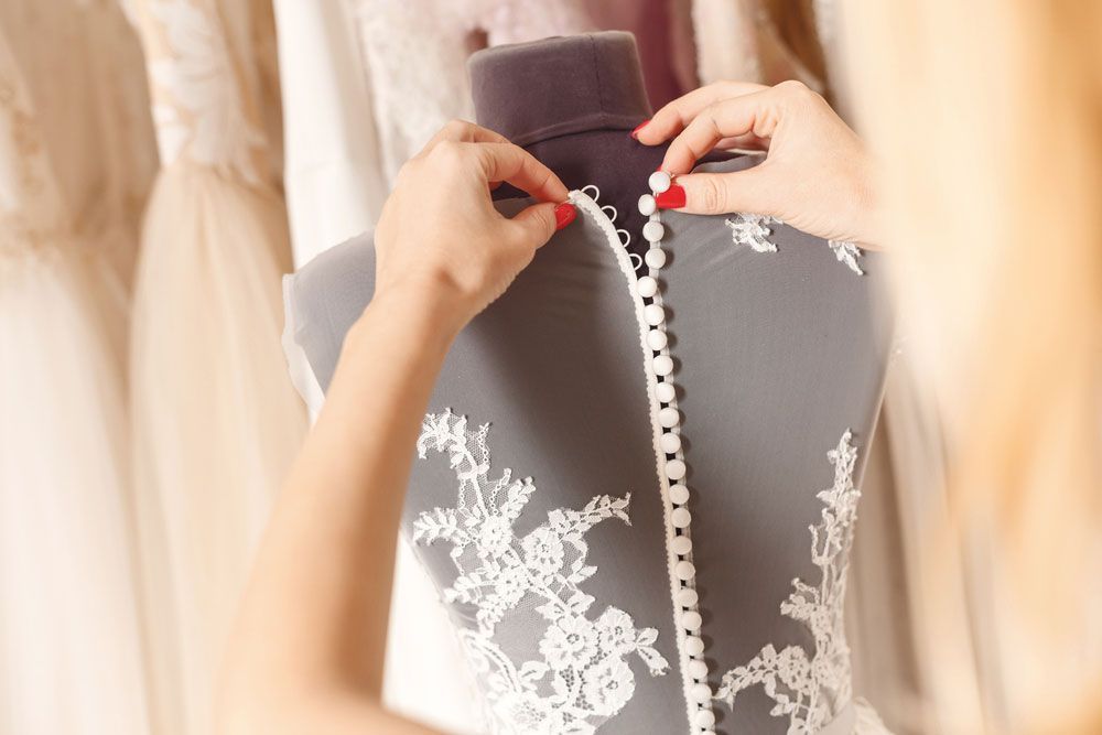 A Woman Is Measuring The Back Of A Wedding Dress — Shop Fittings Office Furniture Materials Handling In Smithfield, NSW