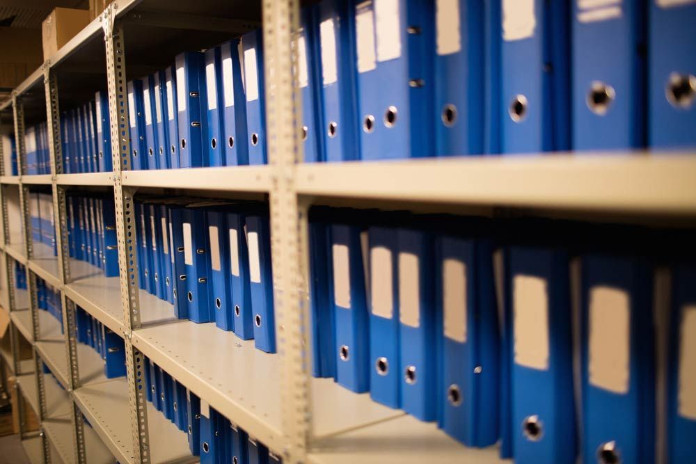 A Row Of Shelves Filled With Blue Binders — Shop Fittings Office Furniture Materials Handling In Gosford, NSW