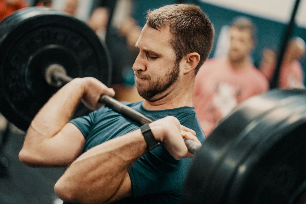 Man lifting a heavy barbell in a gym, with focus and determination.