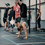 People doing handstands in a gym. A trainer looks on.