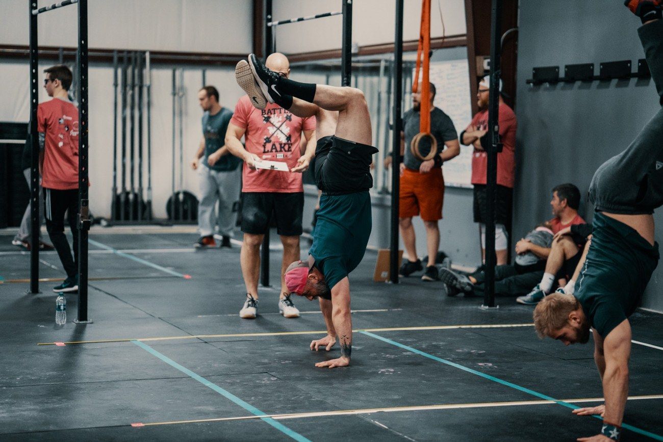 People doing handstands in a gym; others watch or rest.