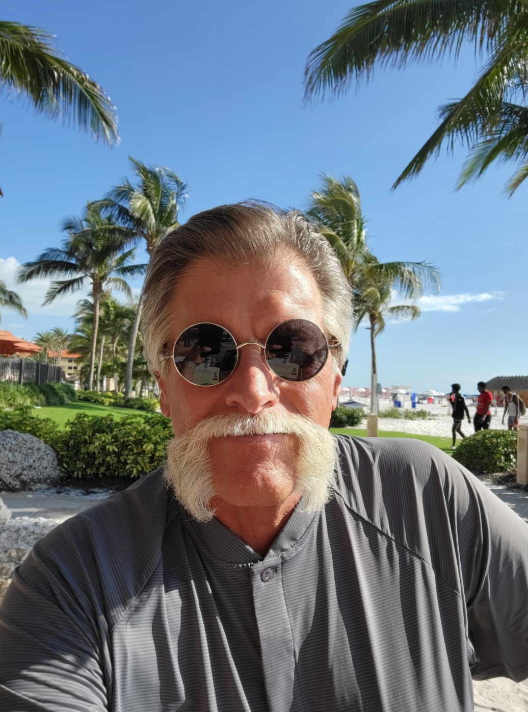 Man with graying hair, mustache and mutton chops, wearing glasses and patterned shirt.